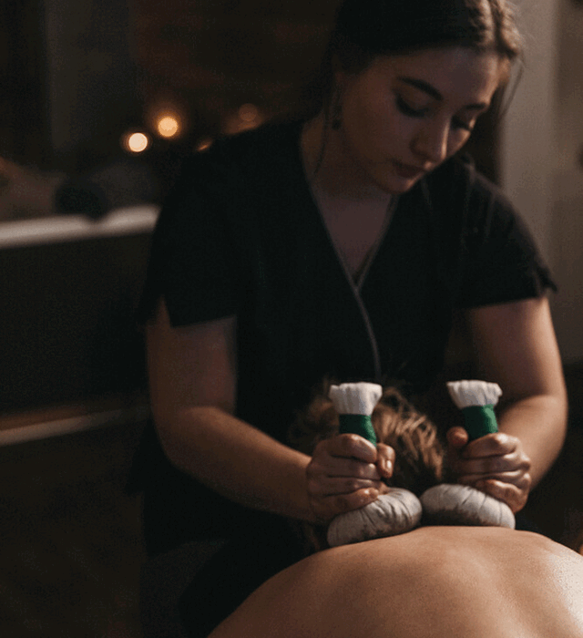 Masseurin bei einer Kräuterstempelmassage im Wellnesshotel Nesslerhof in Großarl, Salzburger Land.