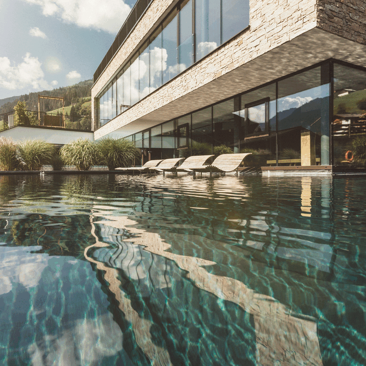 Entspannung pur bieten die hölzernen Liegen im Pool vor dem Wellnesshotel Nesslerhof in Großarl.